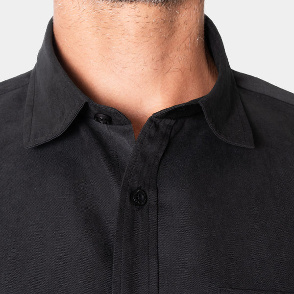 Detalle del cuello y botones frontales de la camisa negra, en modelo | hover: Negro