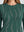 Detalle del cuello redondo y aplicaciones de pedrería en forma de ondas del suéter verde | hover: Verde