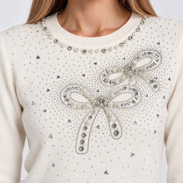 Detalle del cuello redondo y moños de pedrería y perlas en el frente del suéter color hueso | hover: Hueso